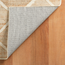 Load image into Gallery viewer, Corner of the rug flipped up to show the bottom on a hardwood floor