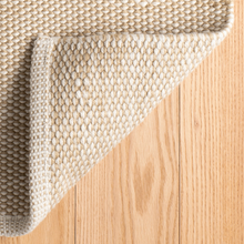 Load image into Gallery viewer, Corner of the rug flipped up on hard wood floors