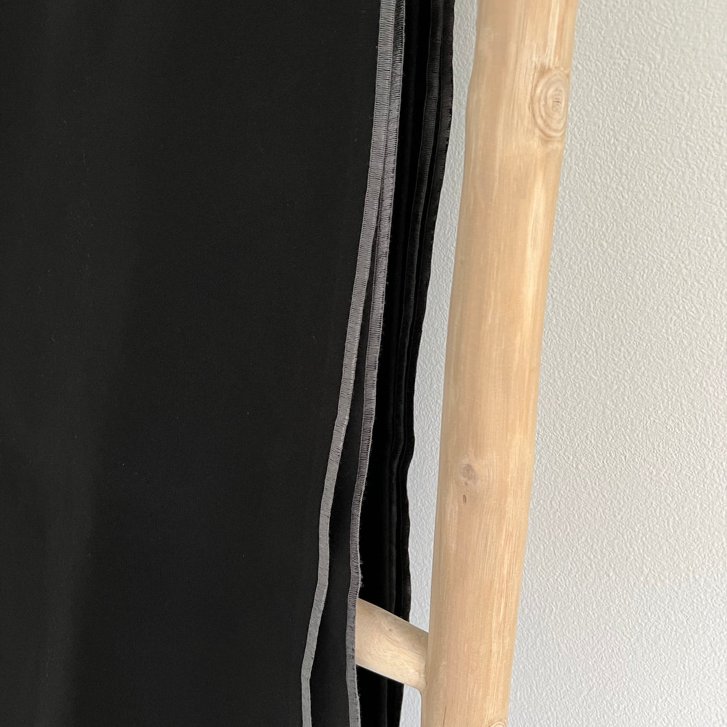 Black throw with a grey edge on a wooden blanket ladder