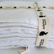 Load image into Gallery viewer, folded up white bedding with a ribbon aorund it on a table