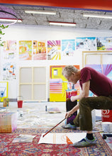 Load image into Gallery viewer, An artist sitting on a can, painting on a canvas laying on the floor in front of him with a long brush. The walls in the room have lots of paintings on them. The ceiling has paintings all over it.