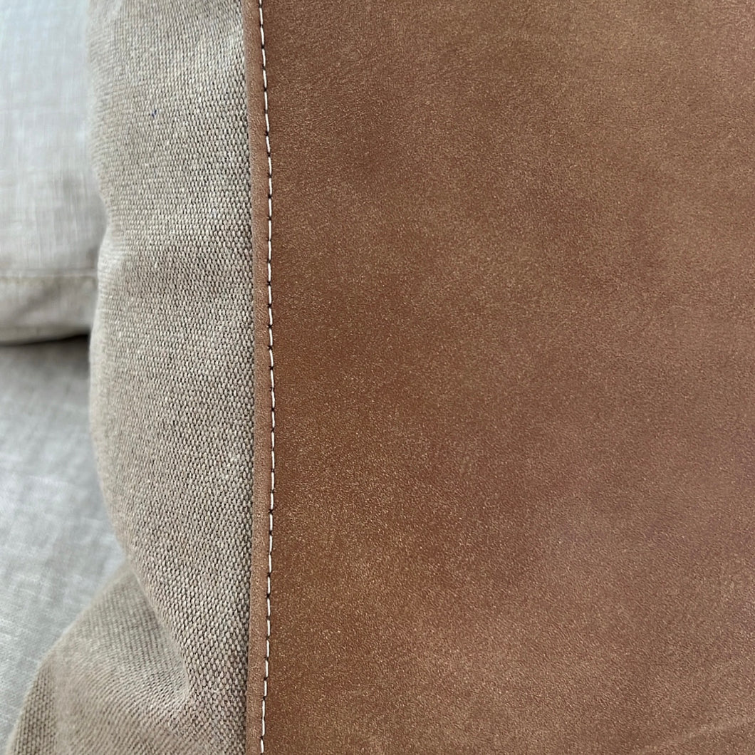 Close up of the tan and leather pillow that includes the white seem on the leather