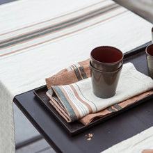 Load image into Gallery viewer, cream libeco table runner with red and grey stripes placed on a table with tea towels on top of it
