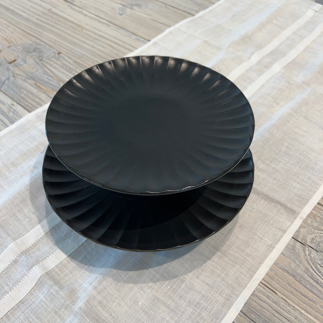 two black cake stands on top of one another on a wooden table