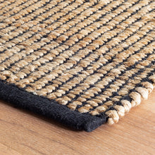 Load image into Gallery viewer, close up of the edge of the black and wicker rug on a wooden floor
