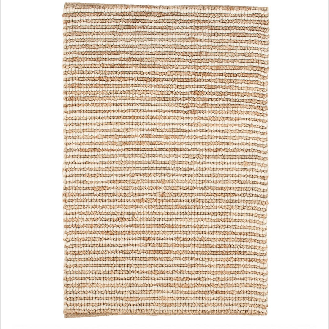 white jute rug laid out on a white floor
