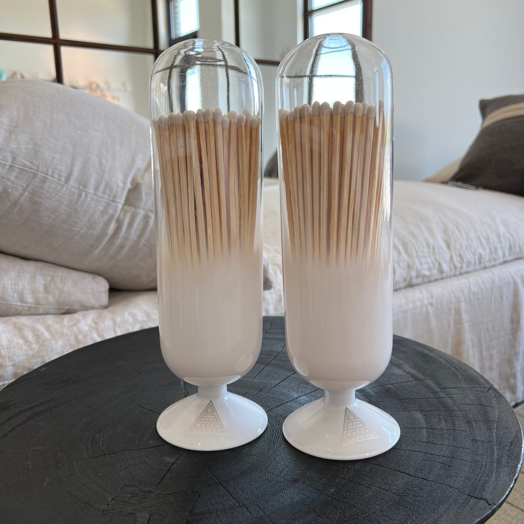 two tall match cloches on a black wooden table