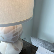 Load image into Gallery viewer, Artsy photo of the stone earthy toned lamp on a brown table 
