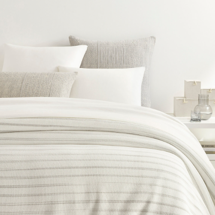 Grey blanket on a white bed setting
