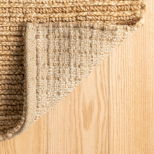 Load image into Gallery viewer, Corner of the natural rug showing the bottom of it on wooden floors
