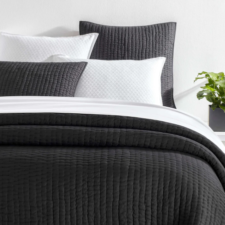Black quilt on a white bed setting
