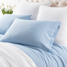 Load image into Gallery viewer, french blue sheets on a white bed setting
