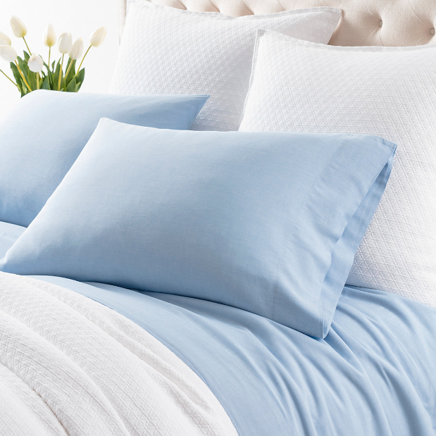 french blue sheets on a white bed setting