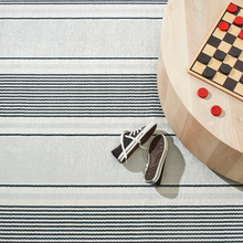 Load image into Gallery viewer, Rug with a wooden coffee table with checker on top. A pair of sneakers is next to the table as well
