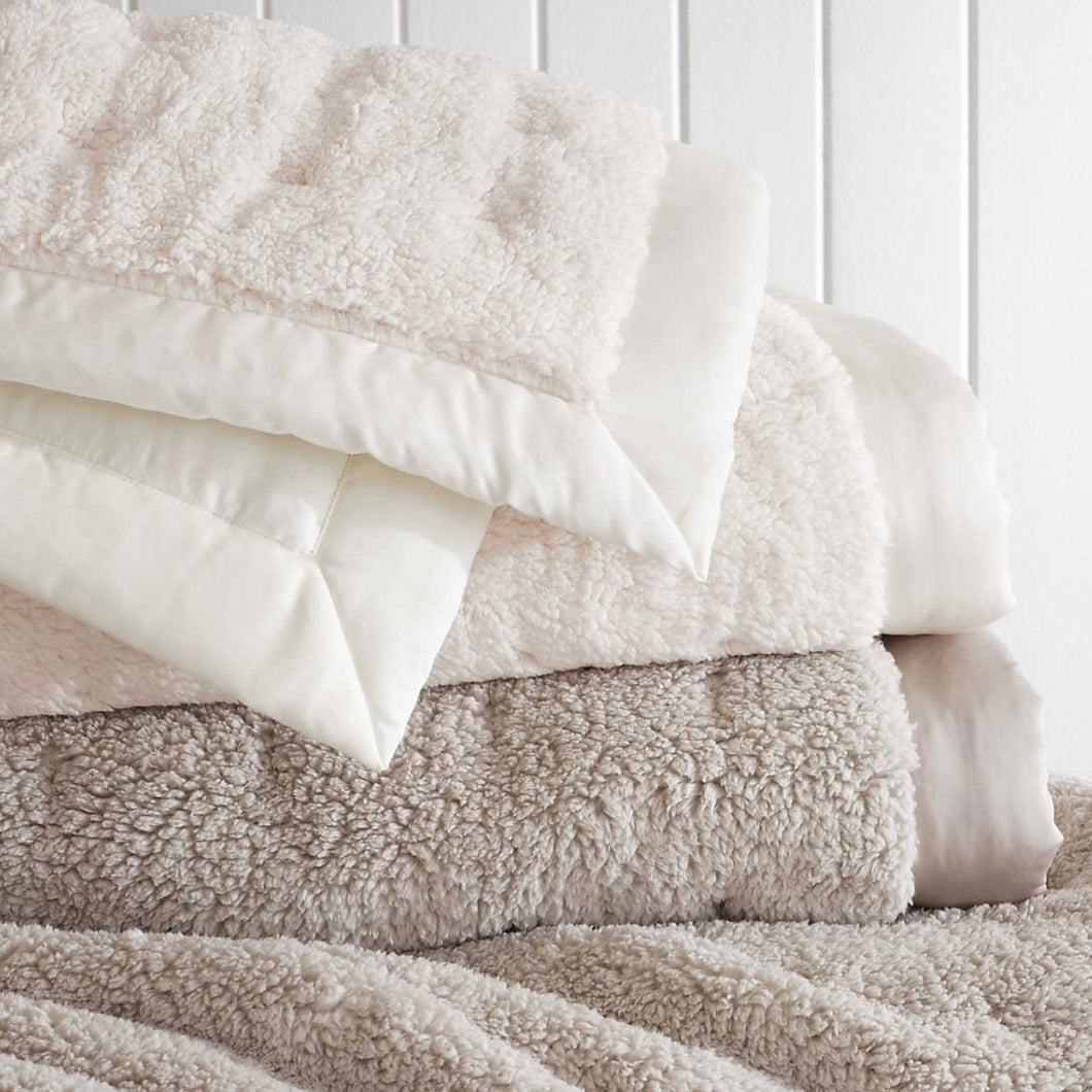 Grey fleece blanket topped with a white fleece throw 