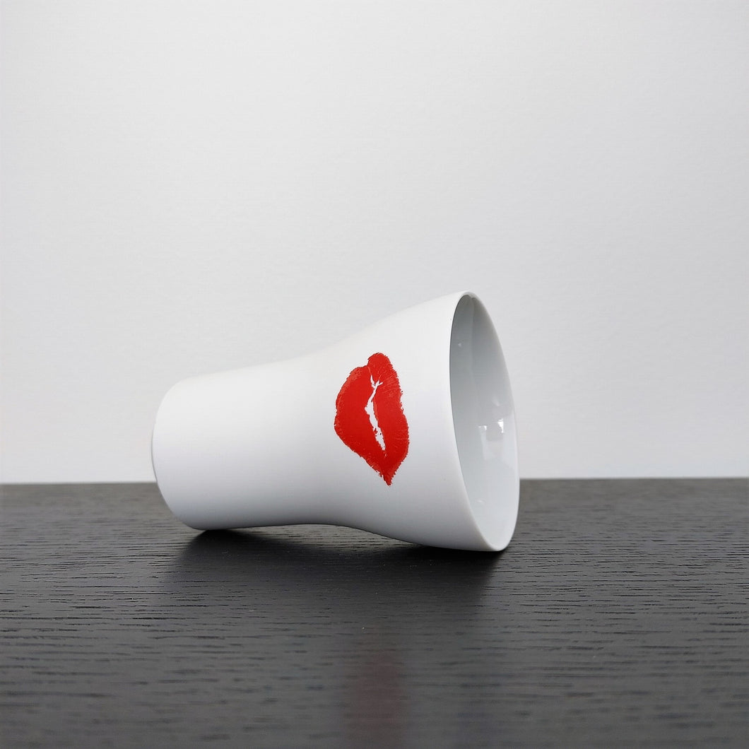 kiss cup laid on its side on a black shelf