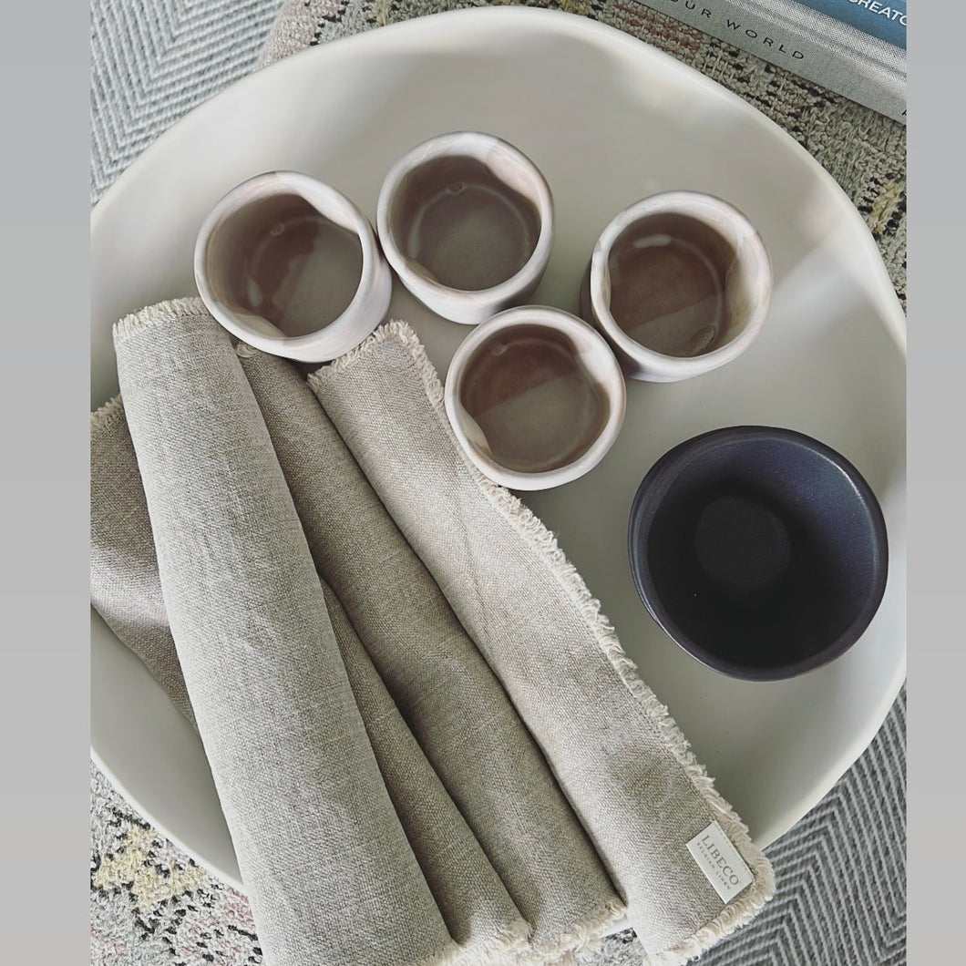 Birdseye view photo of a large white bowl by Alex Marhsall with four tumblers and Libicco placemats 