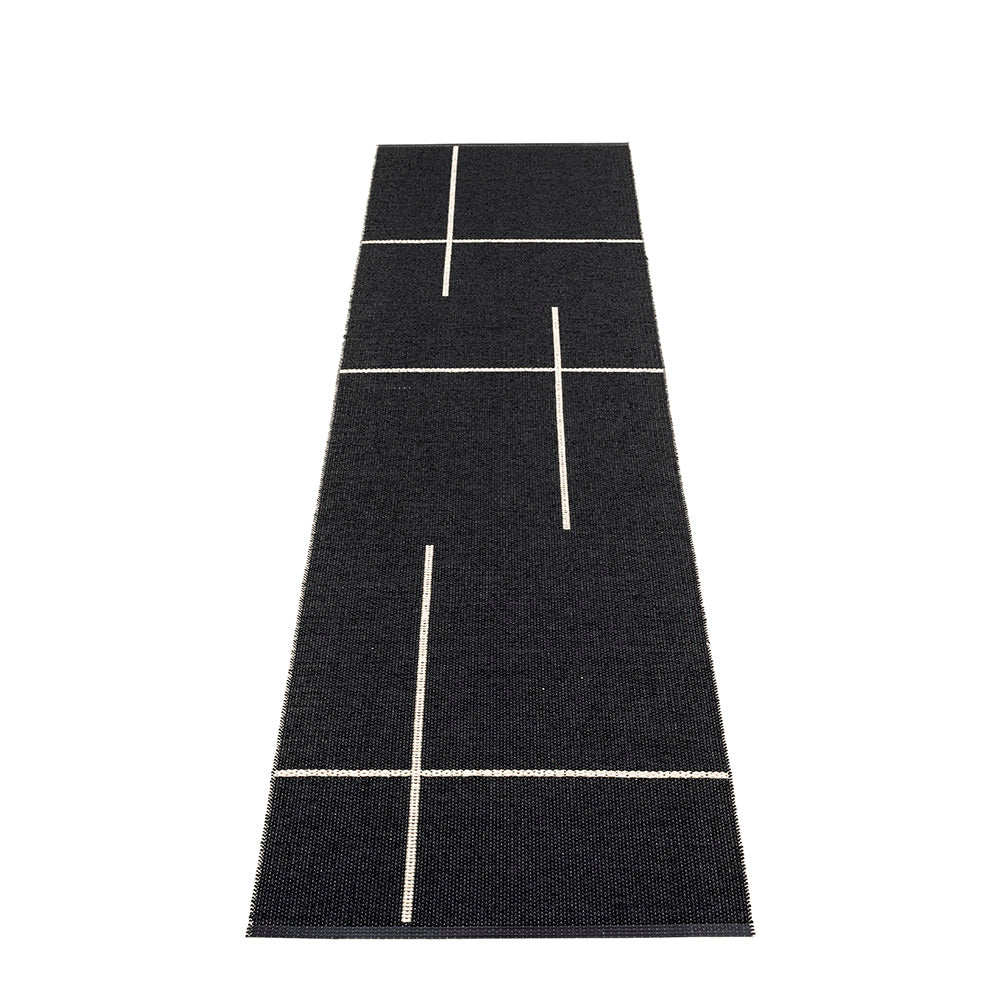 Black rug with white geometric lines laid on a white floor
