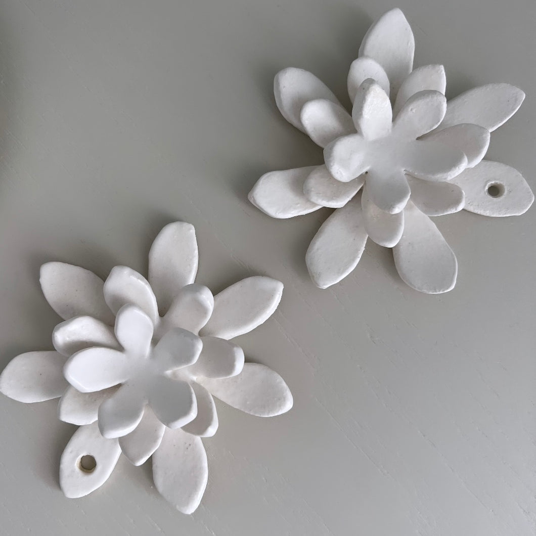 Two ceramic white flowers on a white table