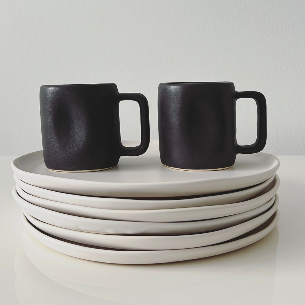 Black Alex Marshall mugs on white dinner plates