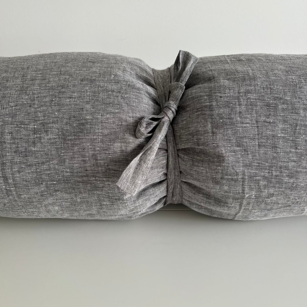 Solid grey pillow rolled up with a tie