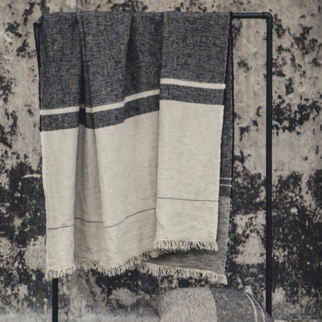 cream, grey striped libeco throw hanging on a metal pipe 