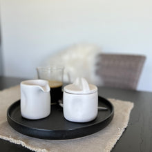 Load image into Gallery viewer, White creamer cup and bowl with lid on a black plate
