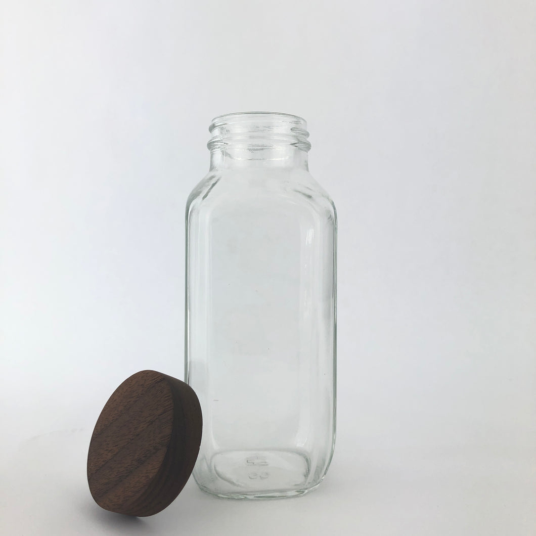 square turnco bottle with the lid set against it