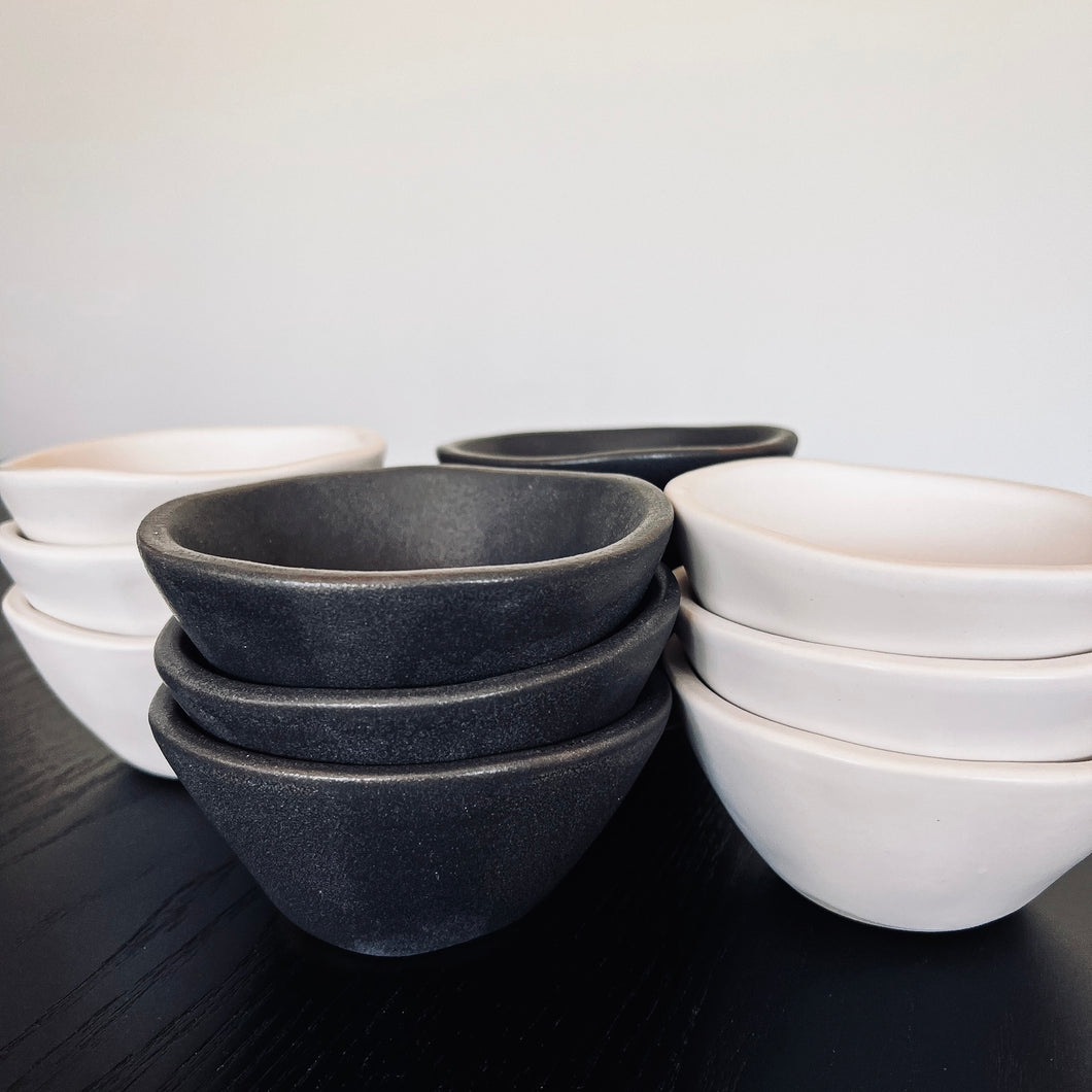 Four stacks of three small bowls. Both white and black Alex Marhsall bowls are featured 