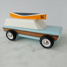 Load image into Gallery viewer, A toy sport utility truck with a wooden canoe on top with the numbeer 76 on it.  The tires have the word CandyGrip on them.  
