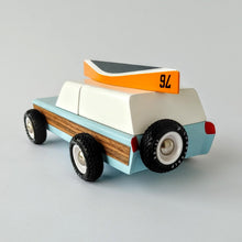 Load image into Gallery viewer, View from behind of a toy sport utility vehicle painted white and blue with an orange canoe on top and a spare tire on the back of the truck.
