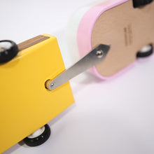 Load image into Gallery viewer, The underside of a wooden toy car and a wooden toy camper showing how to connect them using a metal toy hitch and a recessed hole in the car with a magnate. 
