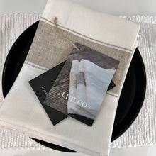 Load image into Gallery viewer, cream and white libeco tea towels with a brochure from libeco on top of the towel

