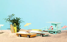 Load image into Gallery viewer, Yellow and wooden toy car from Candylab on a beach seen with another green wooden car

