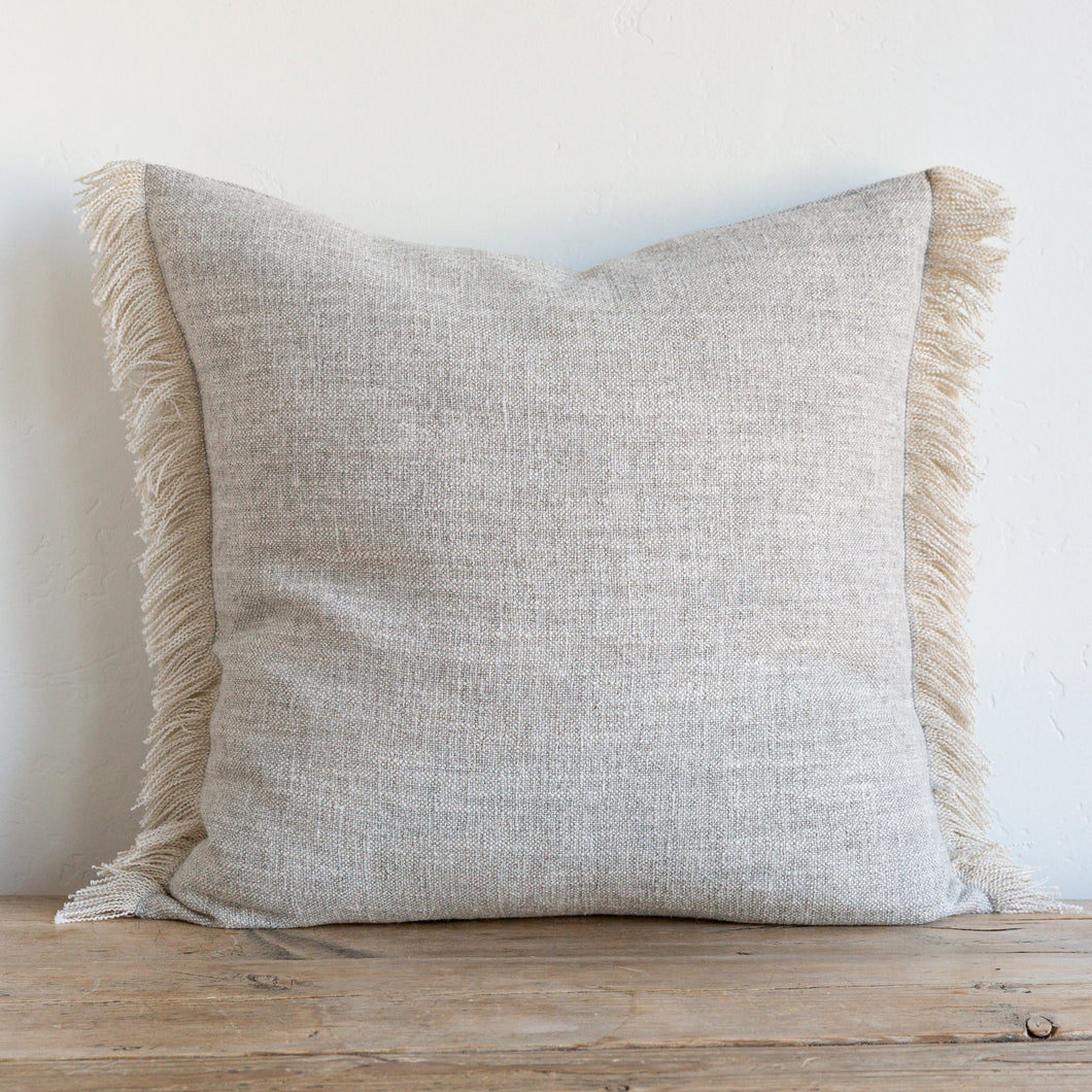 Beige frayed pillow on a wooden bench