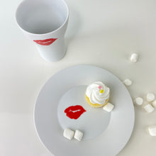 Load image into Gallery viewer, kiss up sitting next to the kiss plate with a cupcake and marshmellows in the frame
