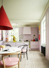 Load image into Gallery viewer, Picture of the inside of the book Living with Art.  Image is of a kitchen with a table and a few chairs and large red cone shaped hanging light above the table.  A white island and a counter are seen in the background.
