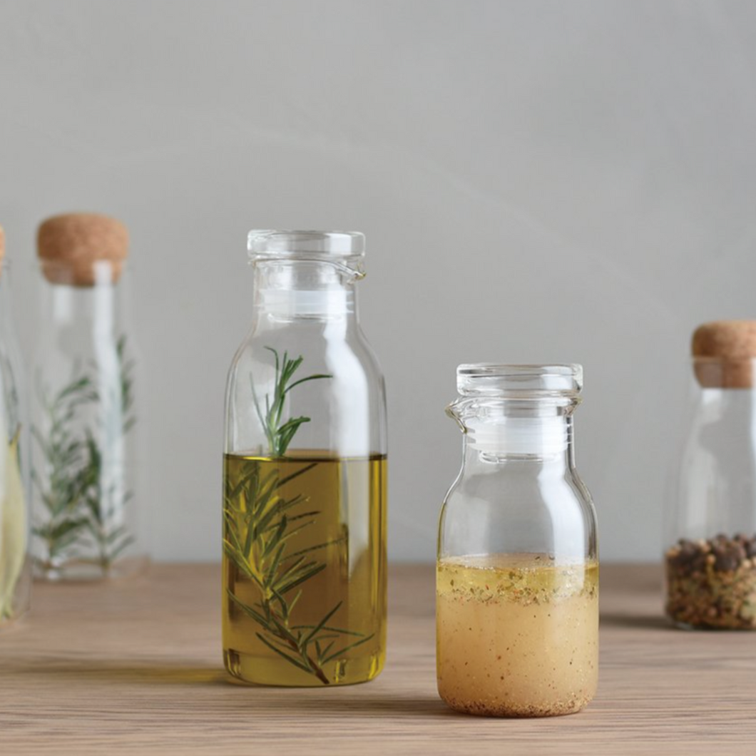 two different sized kinto dressing bottles on a wooden table 