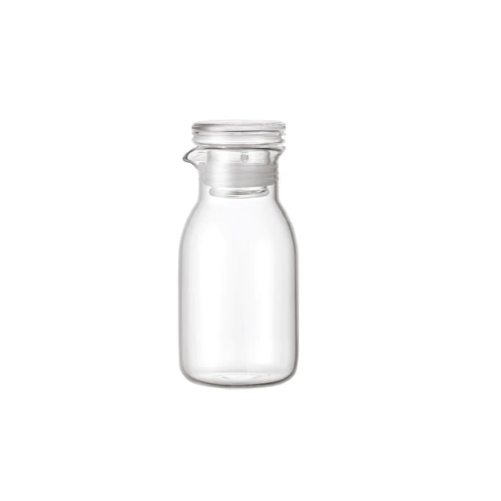 small glass kinto dressing bottle on a white background