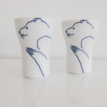 Load image into Gallery viewer, Two white porcelain drinking glasses with sketches of bears in blue.
