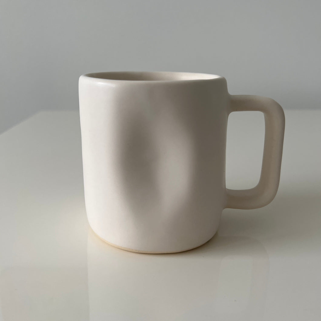 Close up of the white Alex Marshall mug on a white table