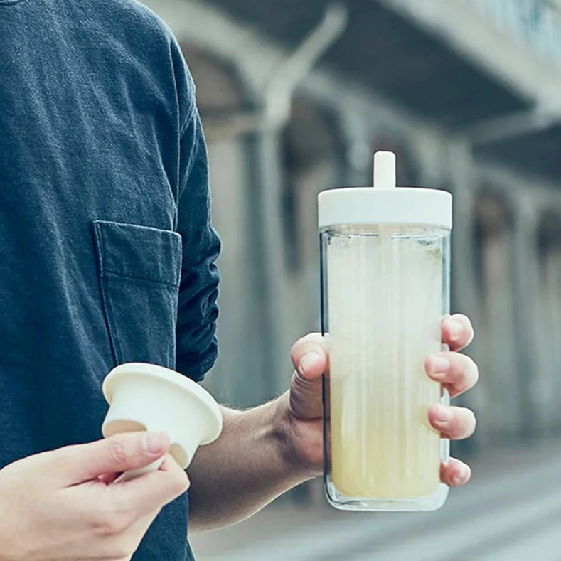 male model holding the unique kinto to go bottle with a drink in it 